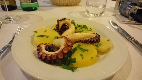 Polipo con patate servito su un piatto bianco